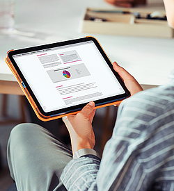 Frau hält ein Tablet in der Hand und liest dort das BKK Service Magazin.