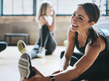 Frau dehnt sich im Sportkurs