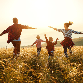 Familie läuft im Sonnenuntergang über Feld